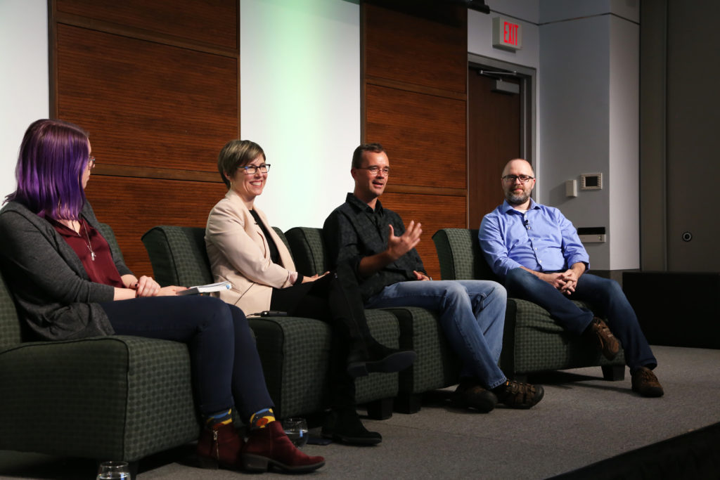 Four speakers sitting on a stage.